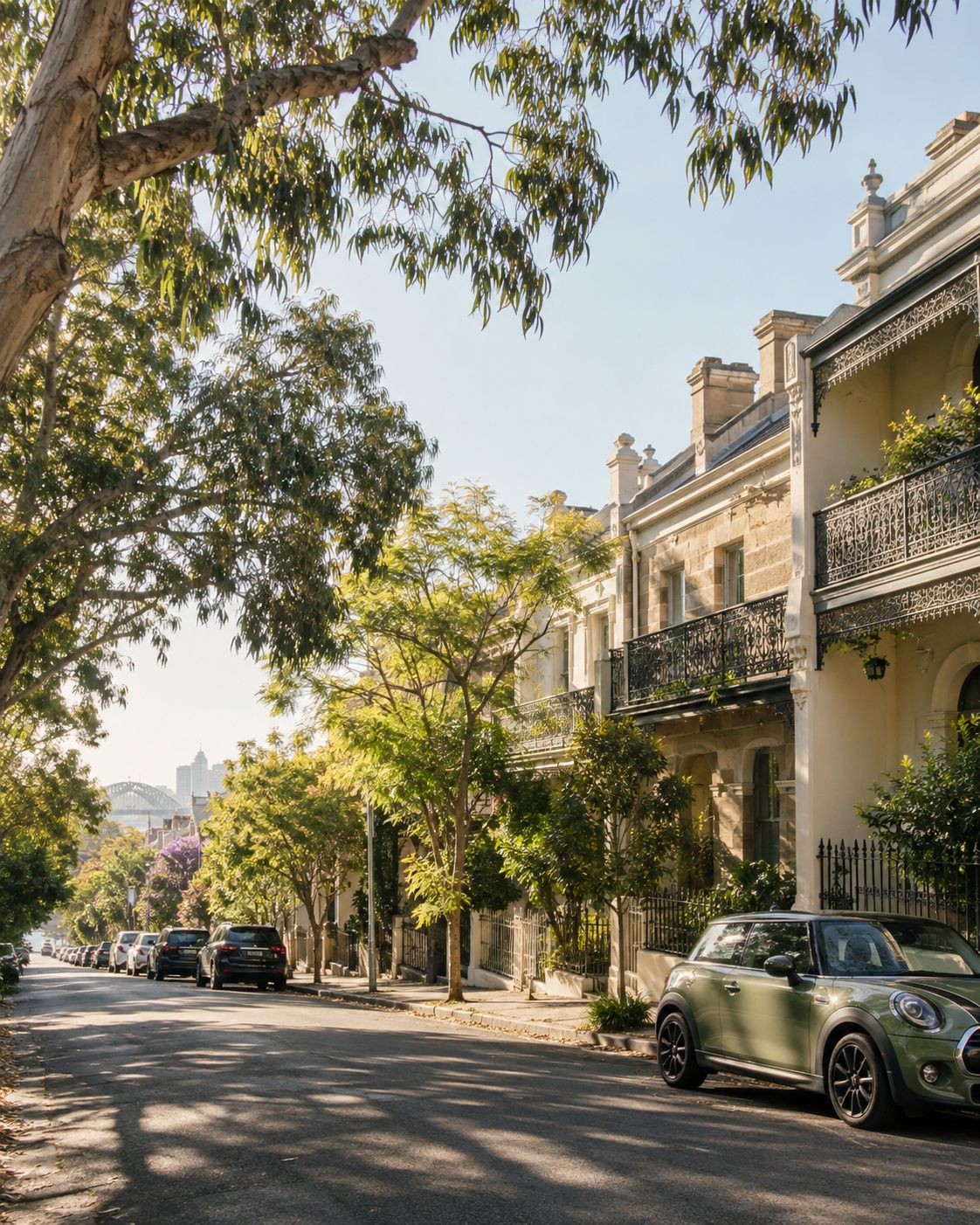 A leafy Sydney-style street with terrace houses and a parked sage-green car